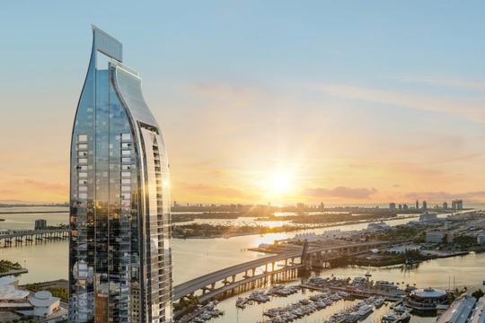 Rendering of Delano Residences and Hotel Miami, a slender glass tower over Biscayne Bay at sunset